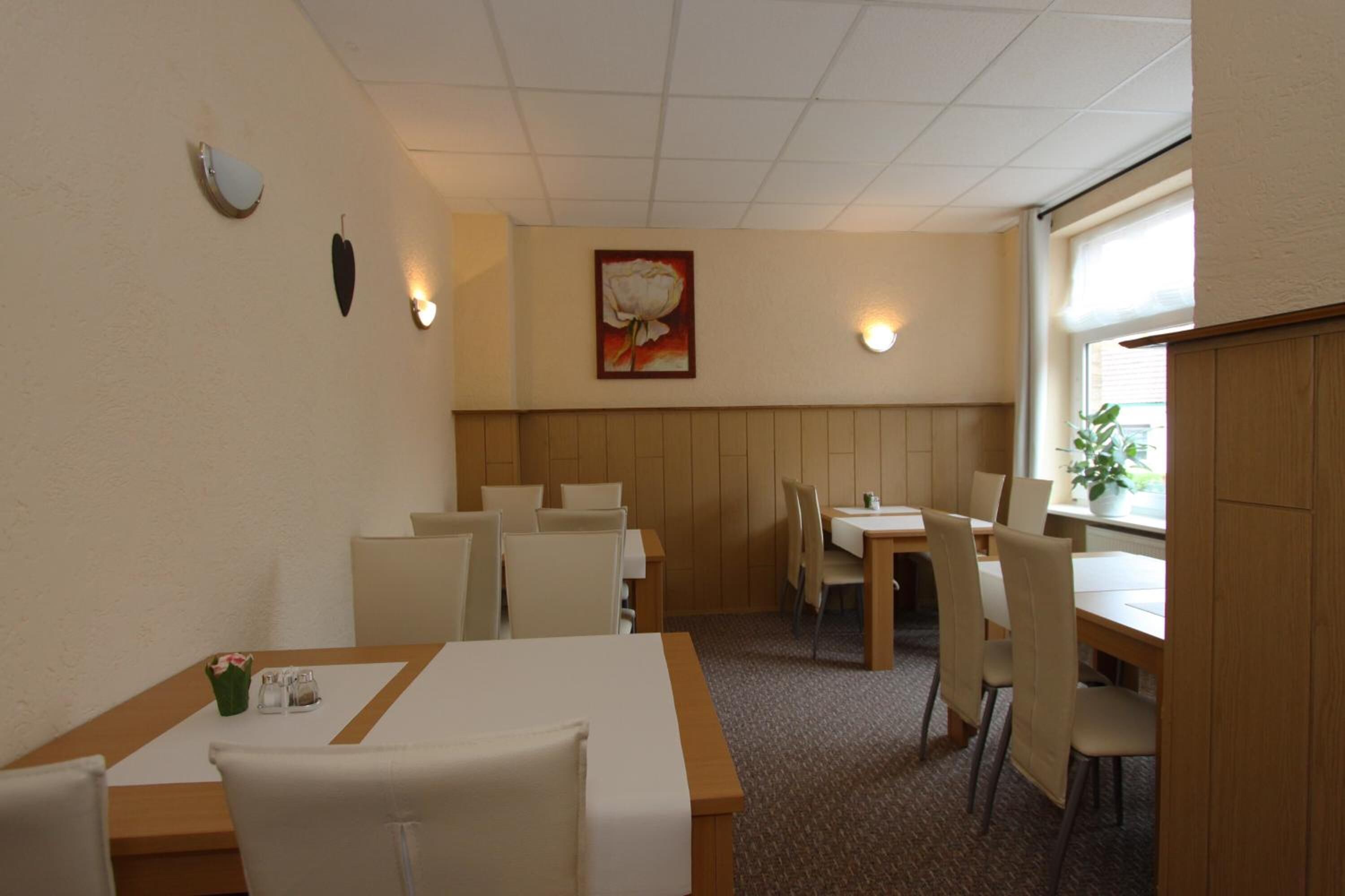 Habitación de hotel con comedor, una cama, ventana con persianas y un cuadro colgado en la pared.