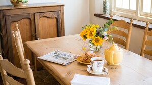 A wooden dining table with a newspaper, a cup of tea, a yellow teapot, and a vase of sunflowers. - One Bedroom, Two Bath, Sunset Views & Kiva Fireplaces. Walk Downtown! (Santa Fe)