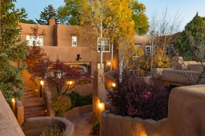 A building with stucco exterior walls, a central staircase, and surrounding vegetation. - One Bedroom, Two Bath, Sunset Views & Kiva Fireplaces. Walk Downtown! (Santa Fe)