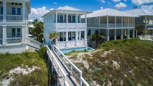 A coastal house with a balcony, a covered porch, and a staircase leading to the entrance. - Direct Gulf Front + Private Walk Down Sleeps 12  (Panama City Beach)