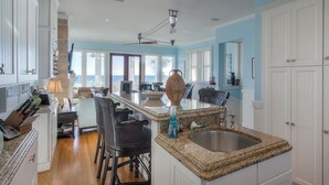 A spacious kitchen with white cabinets, a granite countertop, and a large island with seating. - Direct Gulf Front + Private Walk Down Sleeps 12  (Panama City Beach)