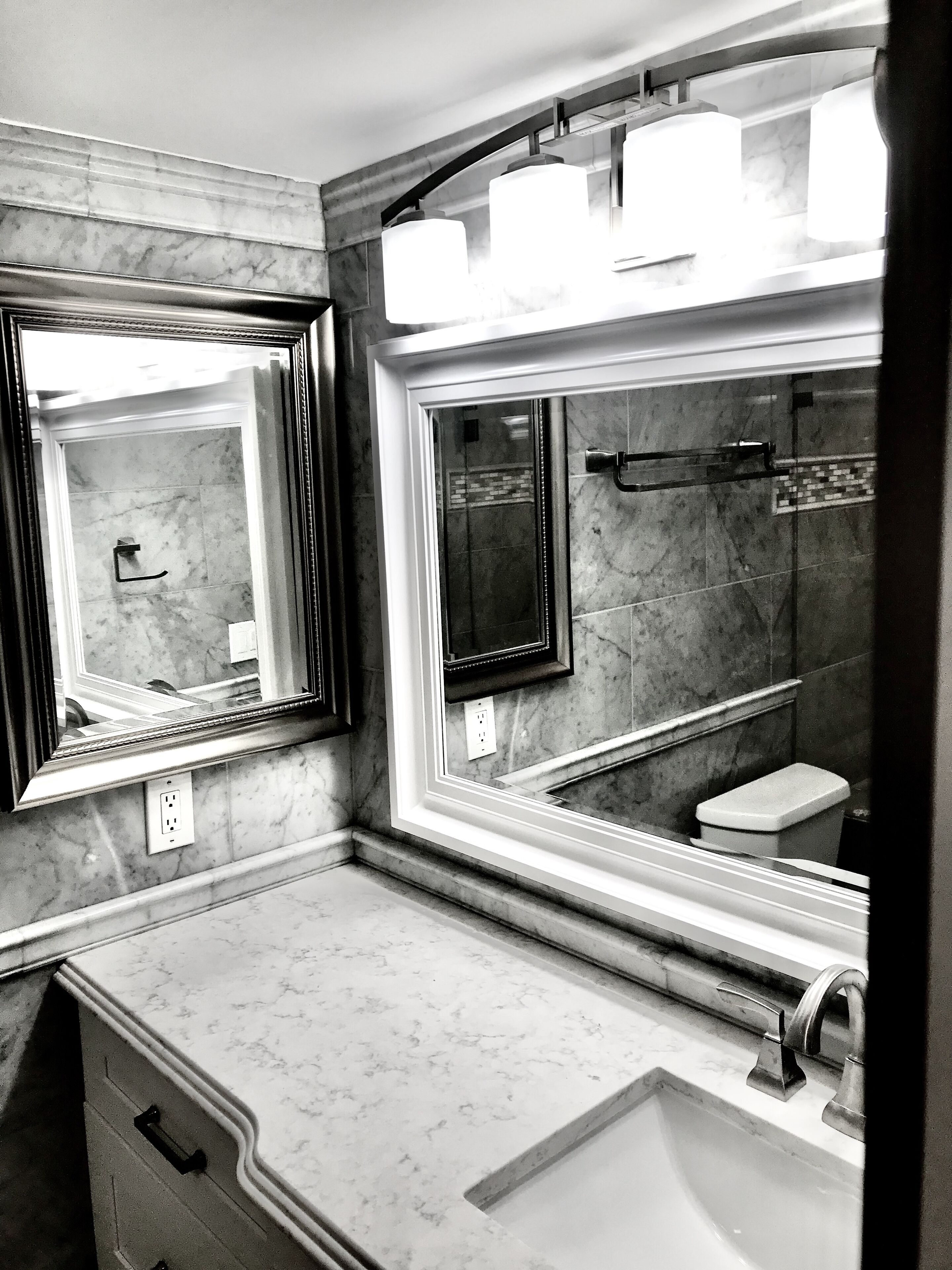 A bathroom with a large mirror, a sink, and a toilet.
