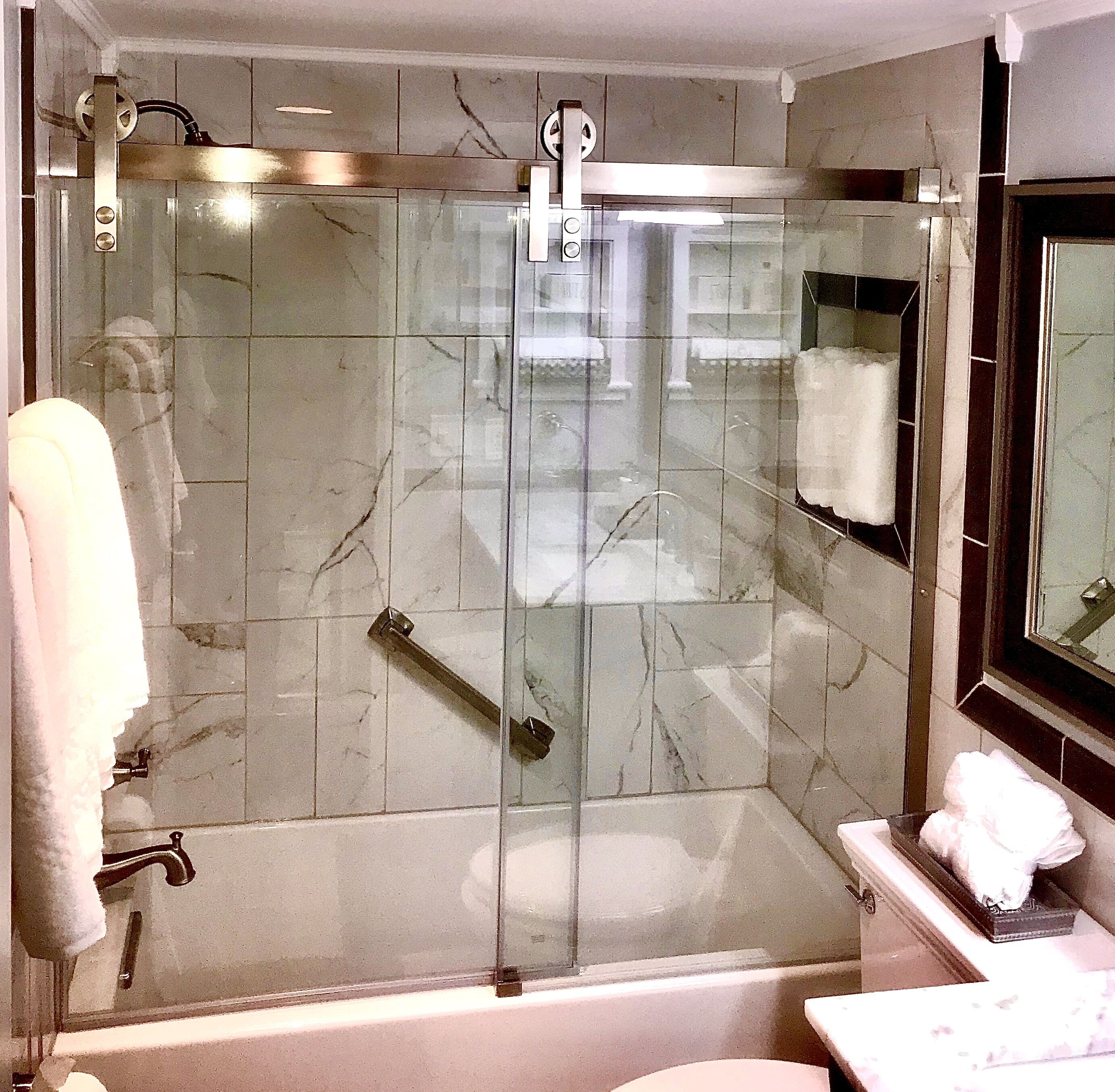 Eine gläserne Dusche mit Duschbrause, einem Handtuchhalter und einem Spiegel über dem Waschbecken.