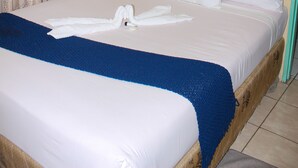 Habitación con una cama individual, dosel, ropa de cama blanca y una manta azul.