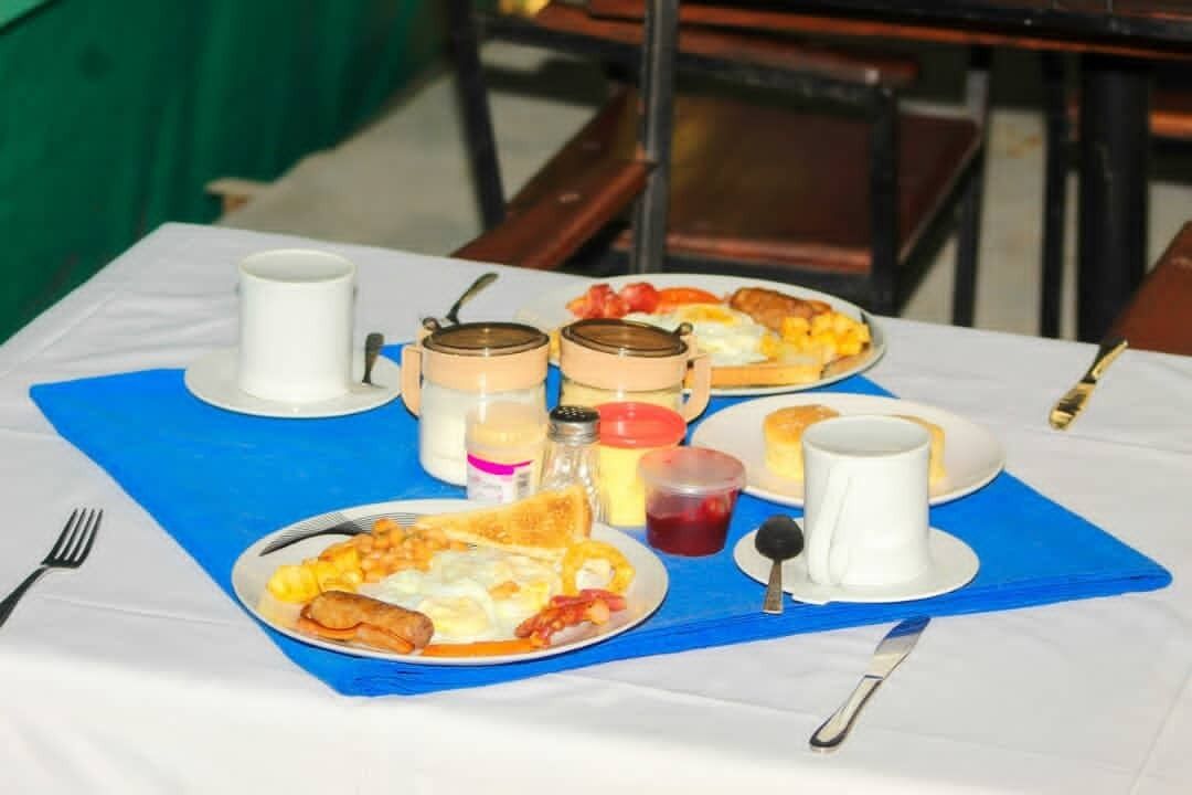 Una mesa de desayuno con platos de comida, tazas y salsas.