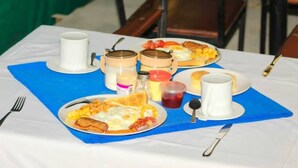 Una mesa de desayuno con platos de comida, tazas y salsas.