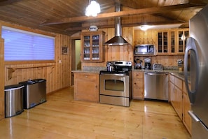 A wooden-paneled kitchen with stainless steel appliances, including a stove, microwave, and refrigerator.