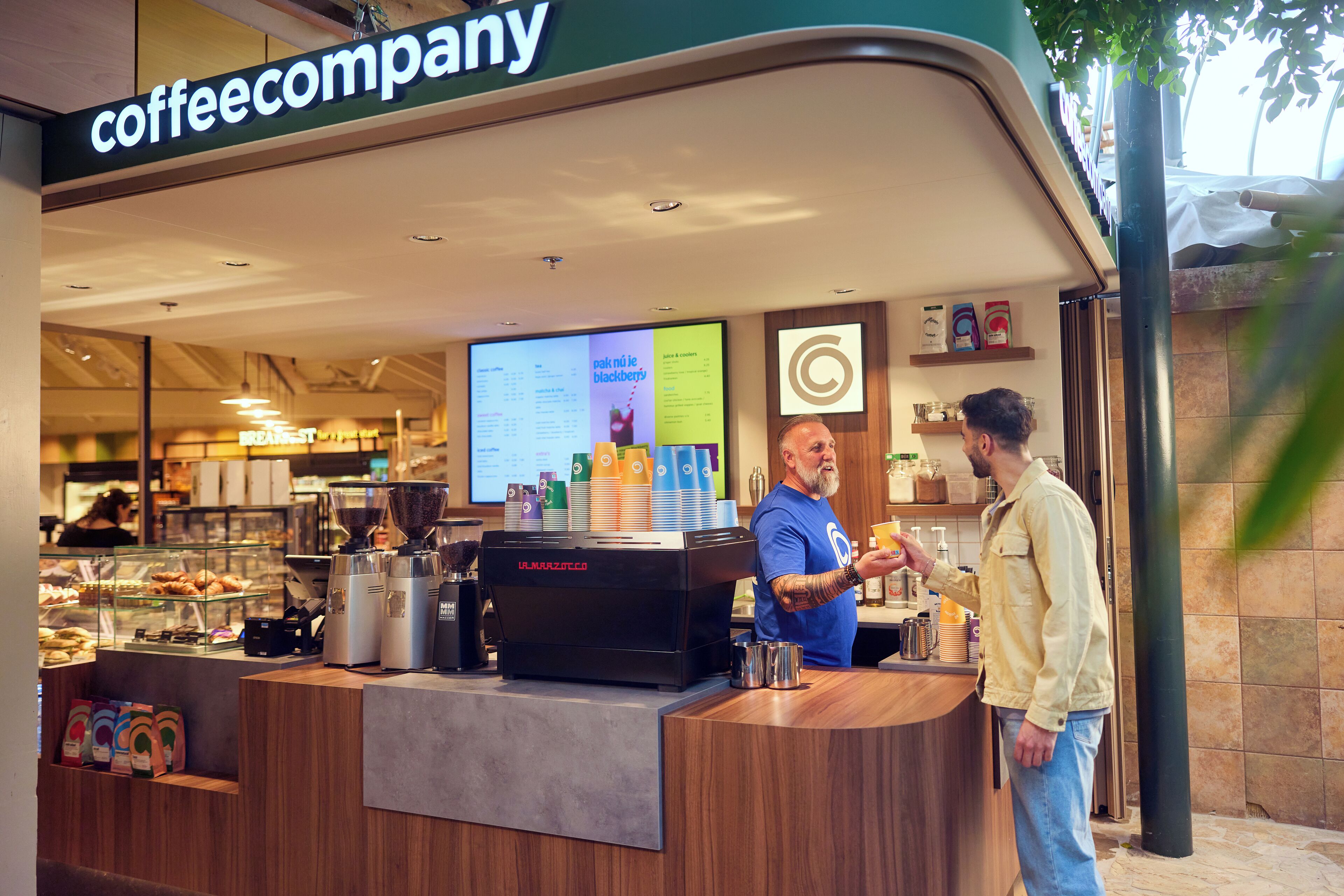 A coffee shop with a counter, coffee machines, and a menu board.