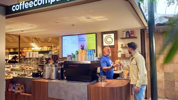 A coffee shop with a counter, coffee machines, and a menu board.
