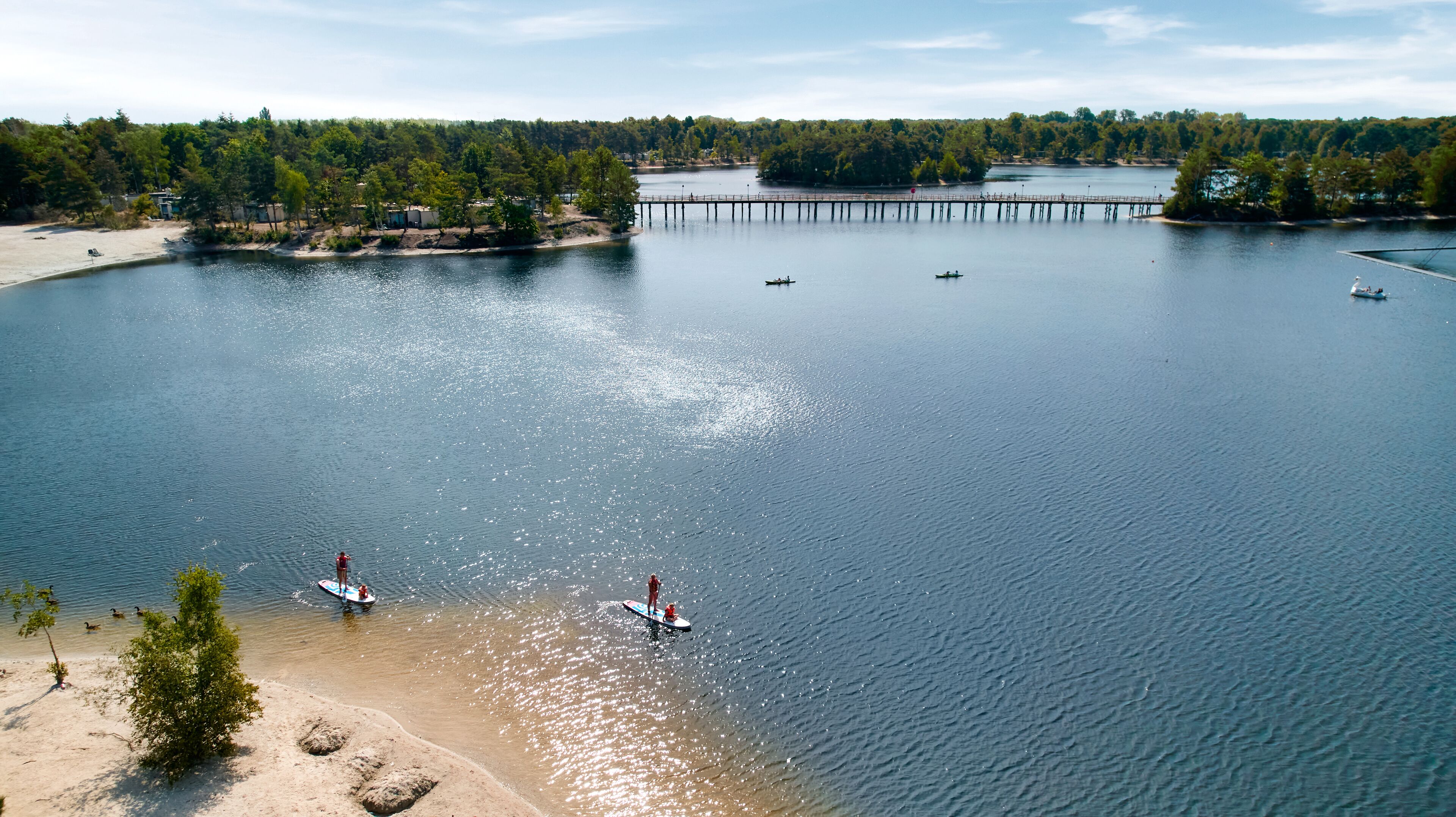 A lake with a pier, boats, and a beach area.