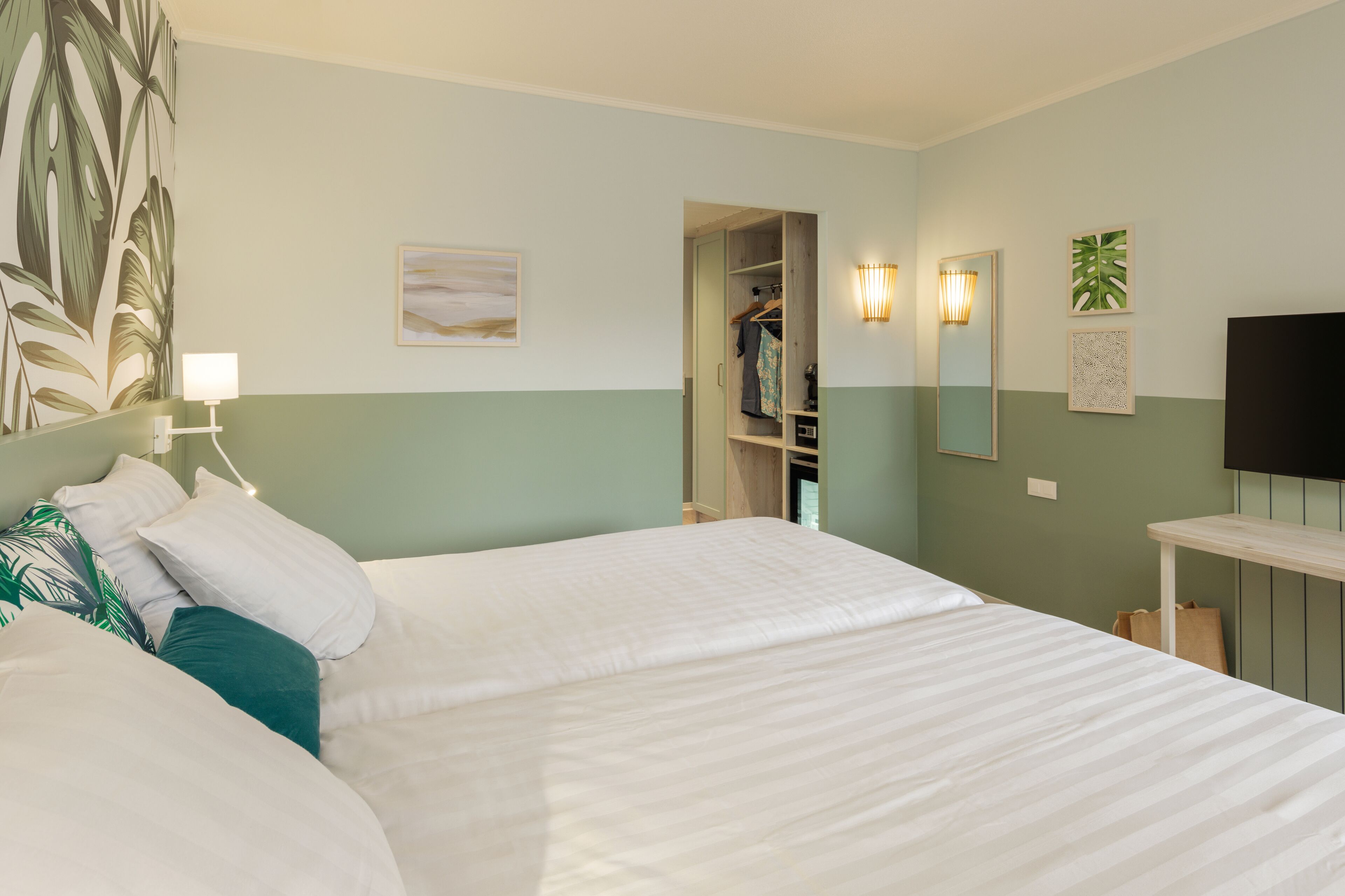 Een hotelkamer met een bed, een kledingkast, een spiegel en een televisie.