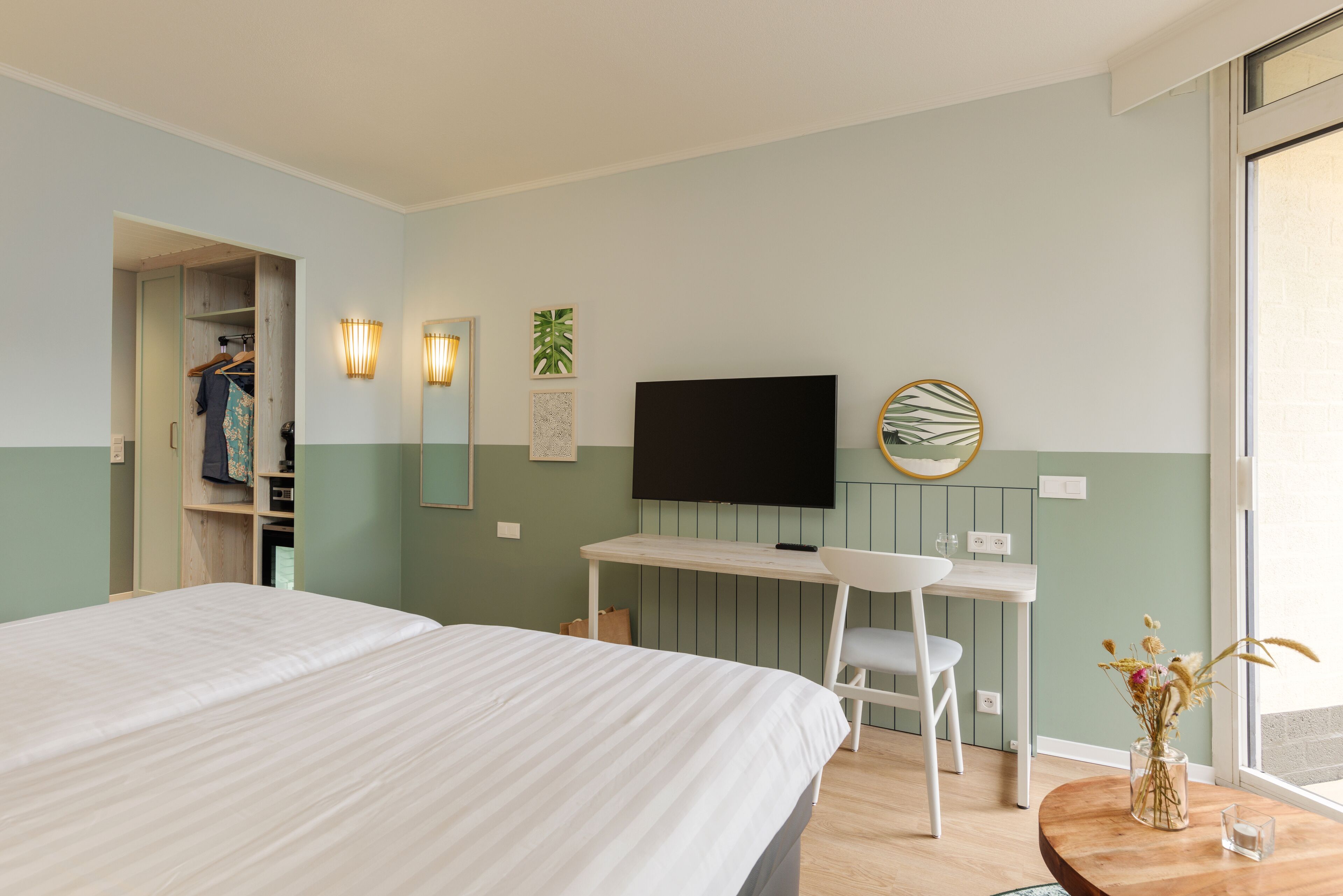 Una habitación de hotel con cama, escritorio, silla, televisión y ventana.