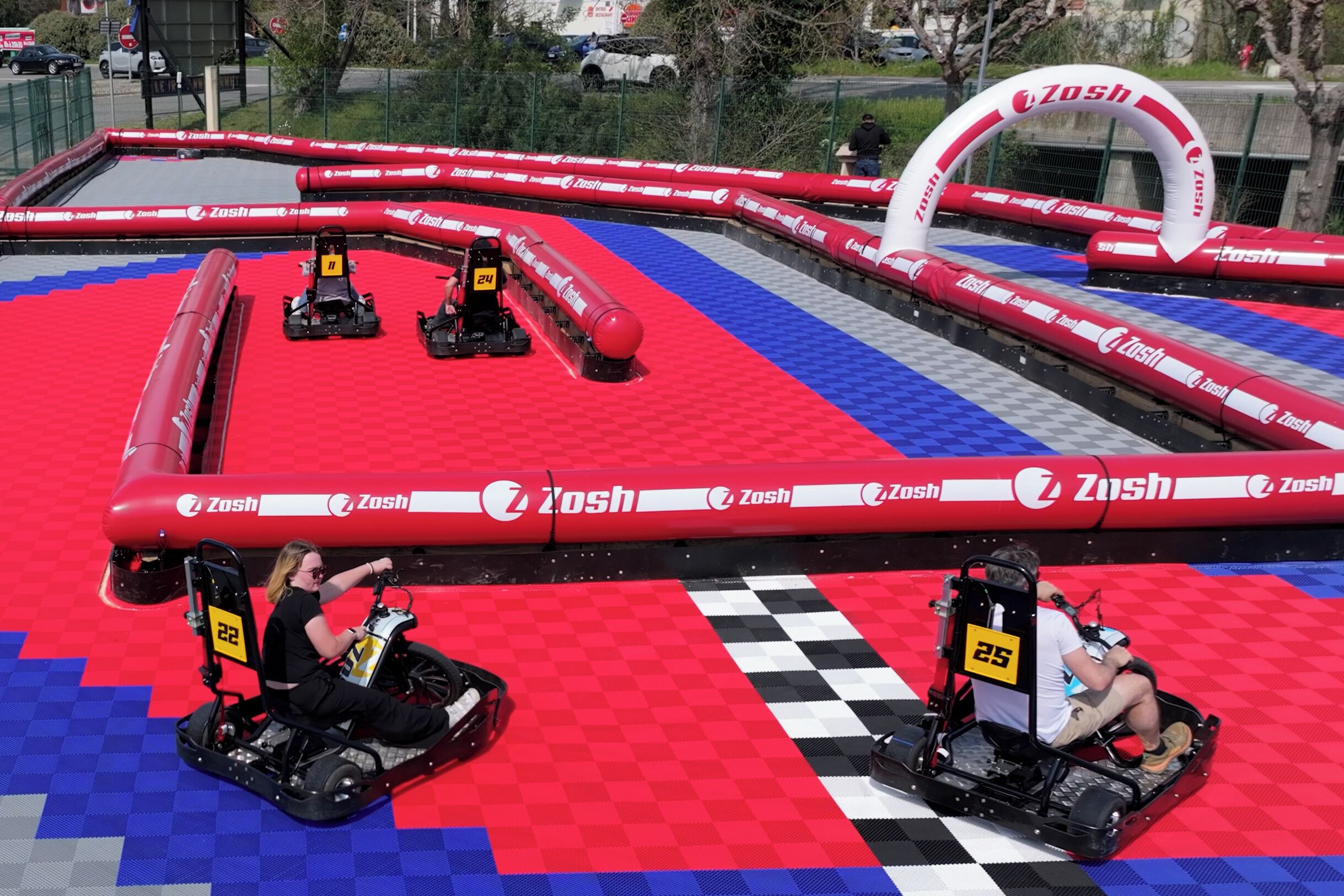 An indoor go-kart track with red and blue checkered flooring and red barriers.