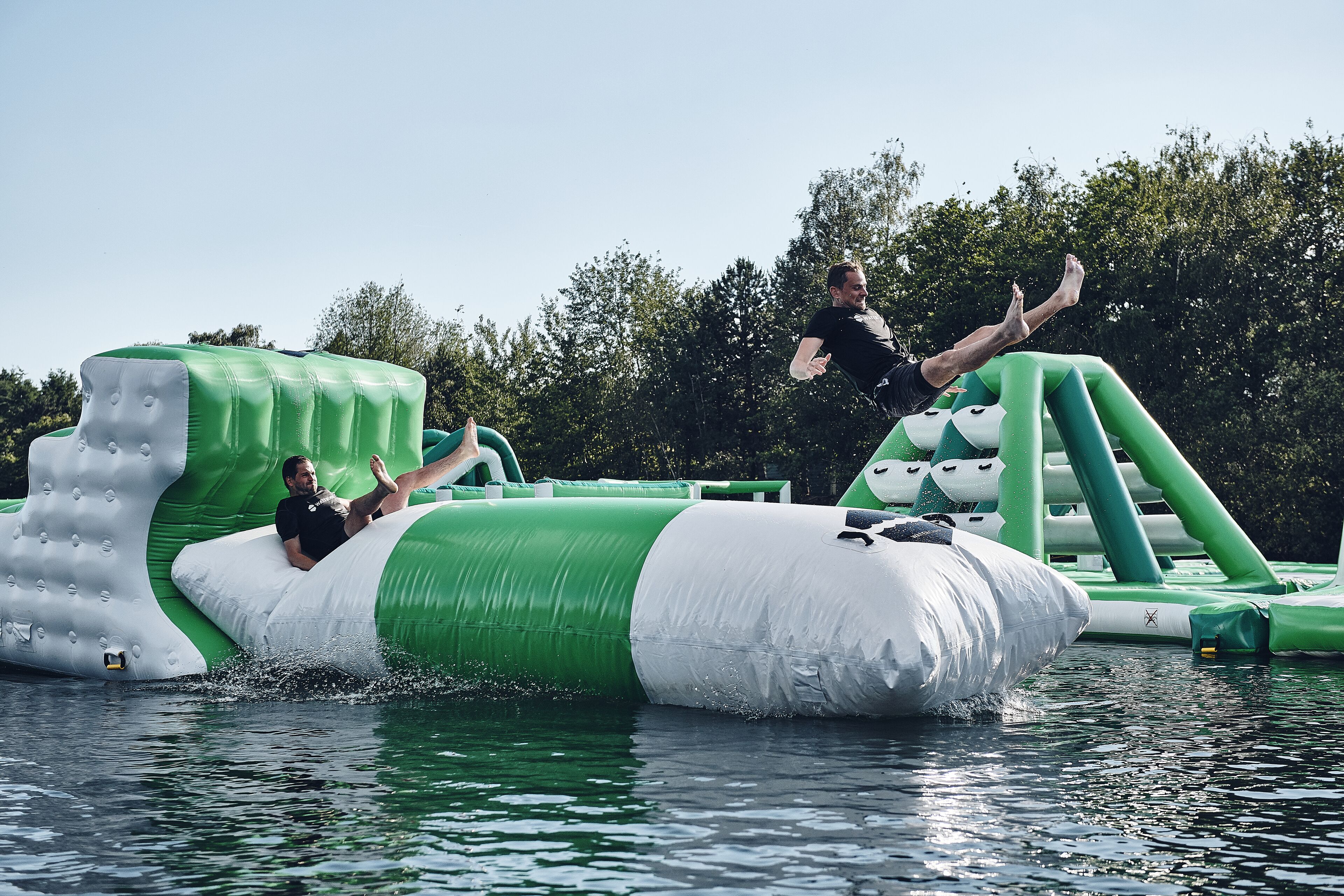 Un homme saute d’une structure gonflable et plonge dans l’eau.