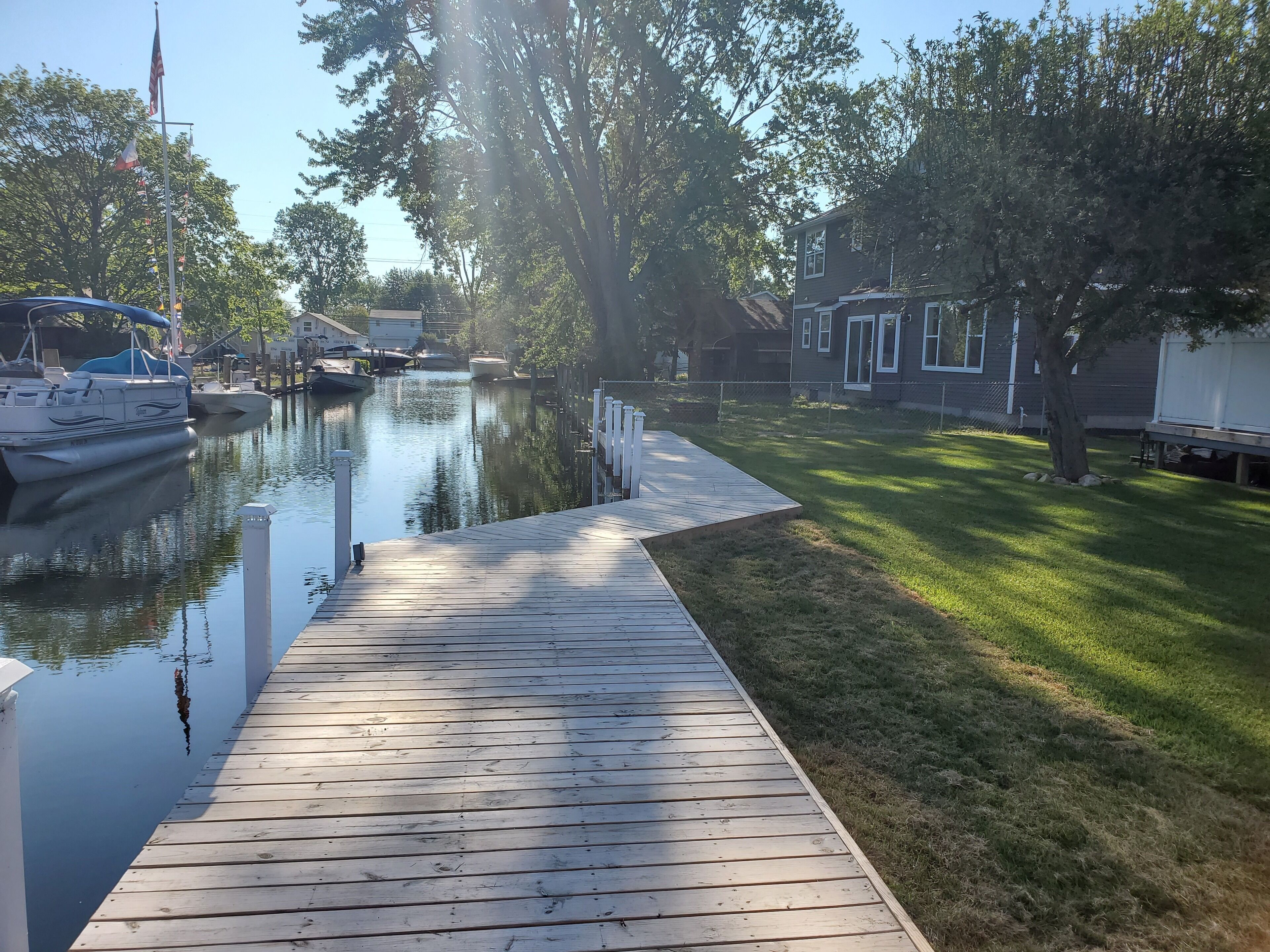 Een houten steiger die uitsteekt in kalm water, met boten aan de linkerkant afgemeerd.