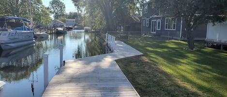 A wooden dock extending into calm water with boats docked on the left.