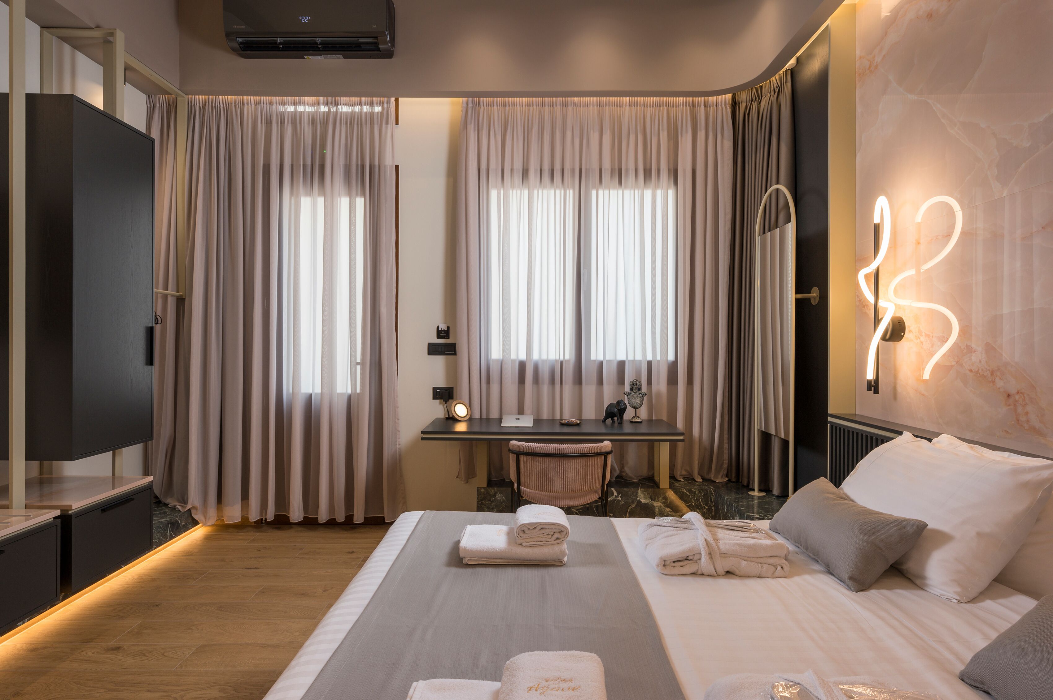 A modern hotel room with a bed, a desk, a TV, and a marble wall.