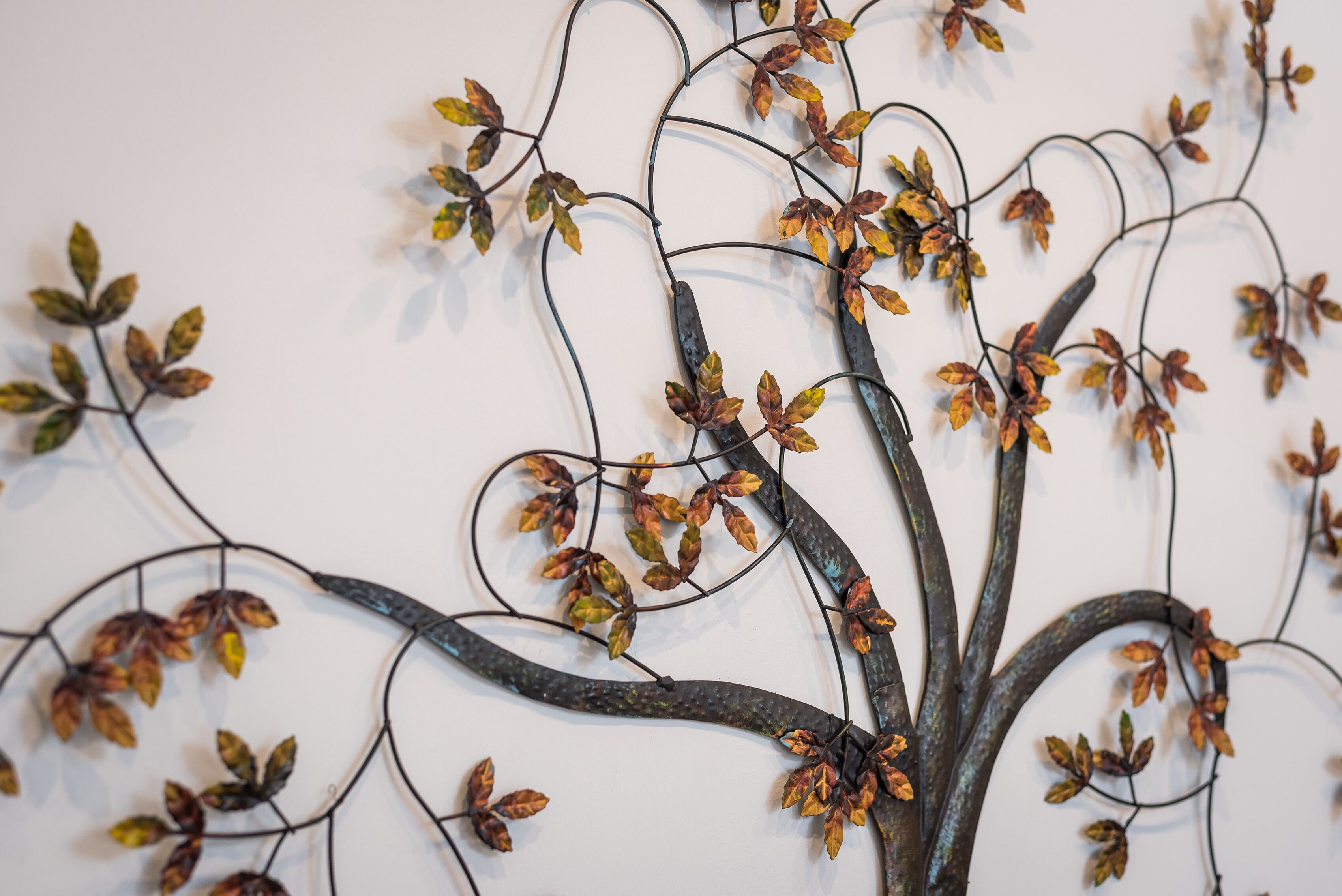 A wall art piece with a tree design made of wire and leaves.