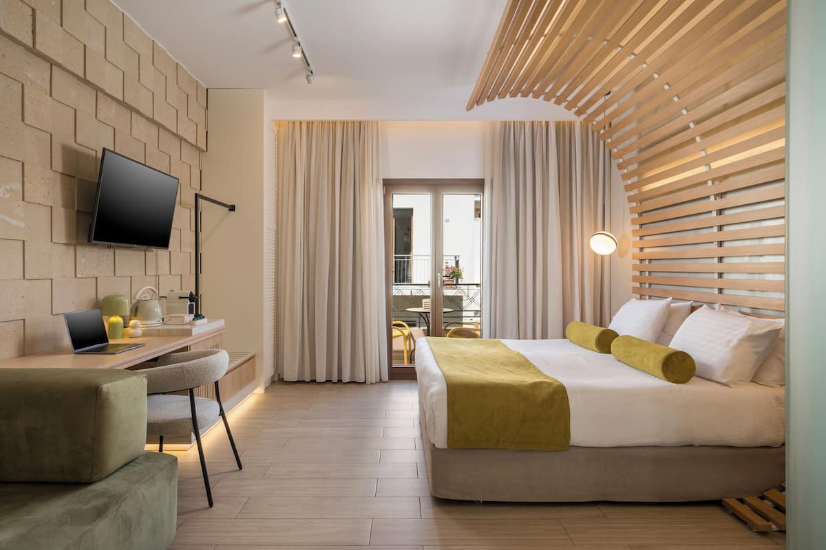 Una habitación de hotel moderna con una cama, un escritorio con una computadora portátil, un televisor de pantalla plana y un balcón con cortinas.