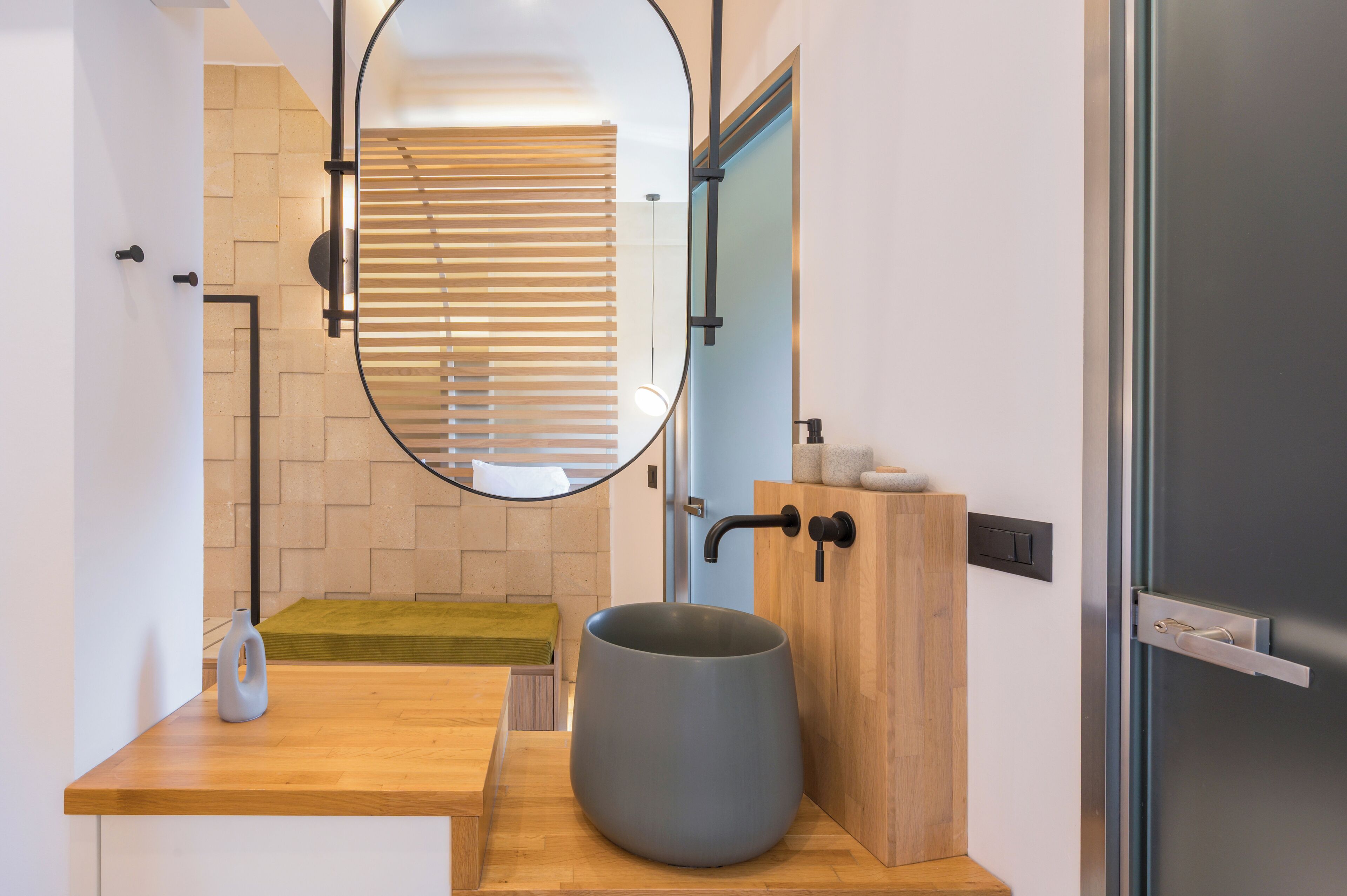 Un baño moderno con tocador de madera, un espejo grande y un lavabo gris.