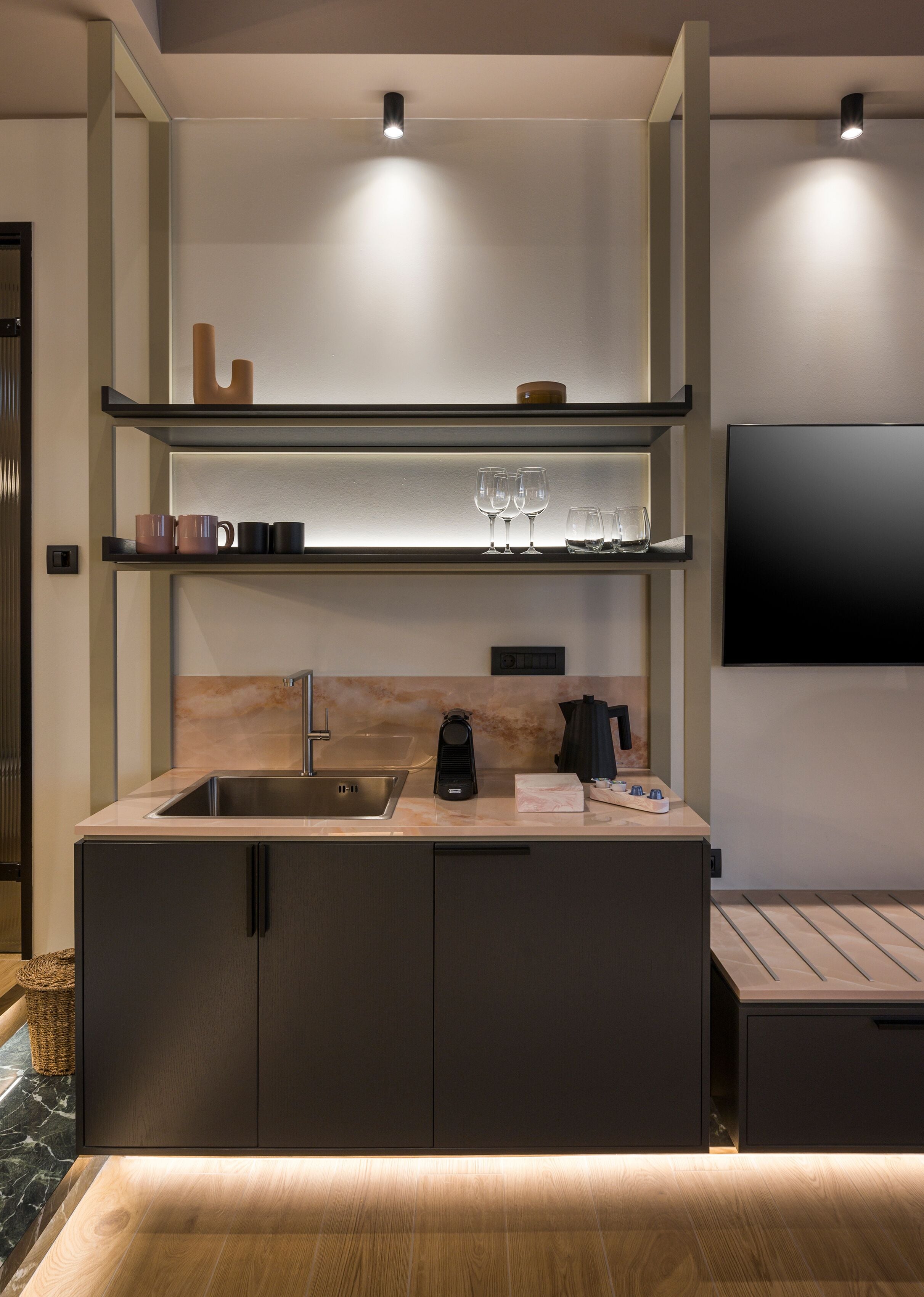 Una cocina moderna con un lavamanos empotrado, una cafetera y un televisor de pantalla plana montado en la pared.