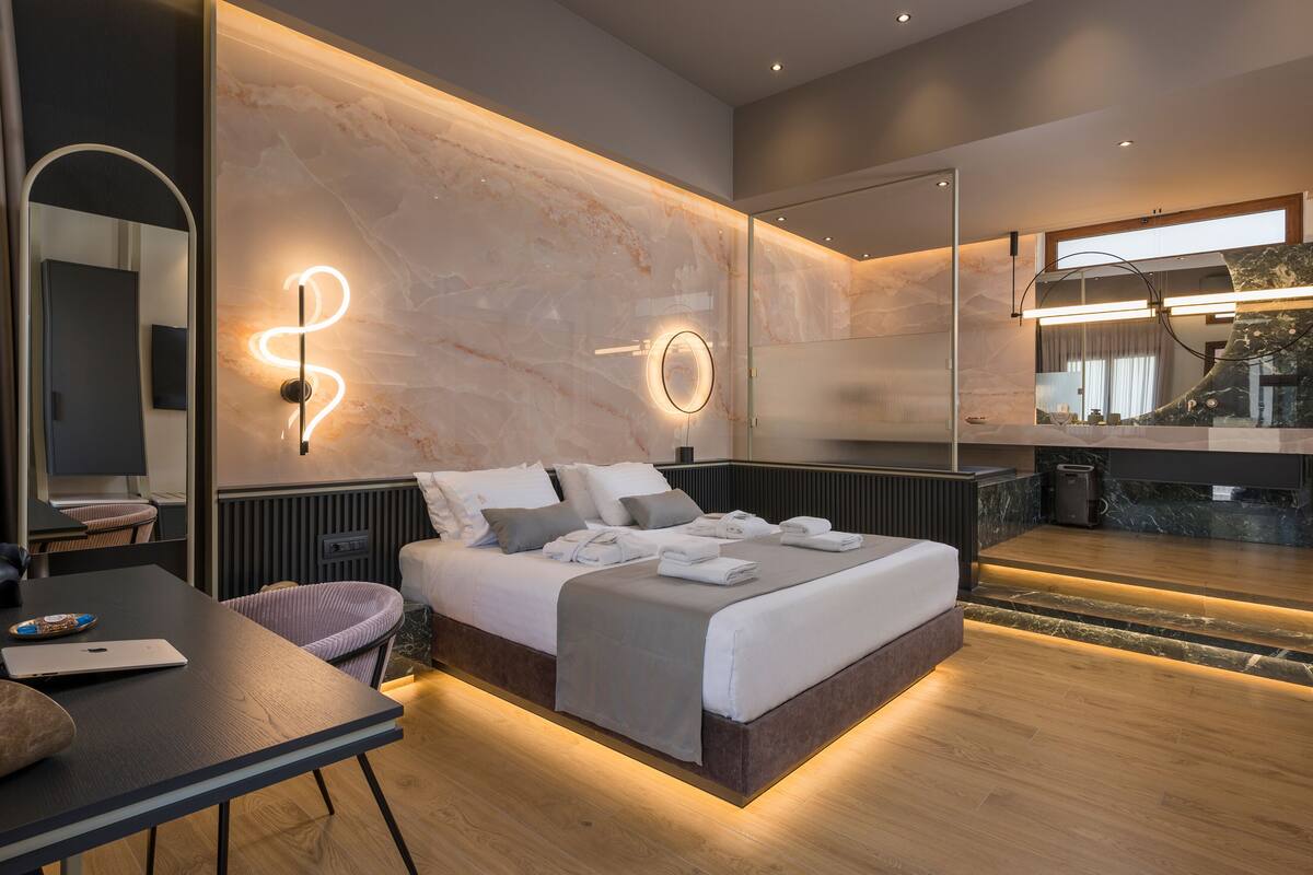 Un dormitorio moderno con una cama grande, mesitas de noche, un escritorio y un espejo.