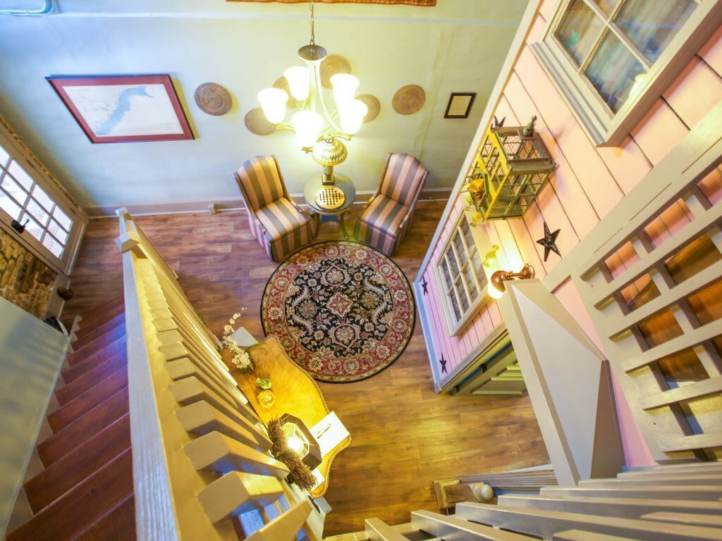 A staircase with a patterned rug, striped chairs, and a chandelier.