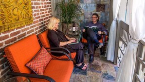 A cozy seating area with a brick wall, a decorative yellow panel, and a potted plant.