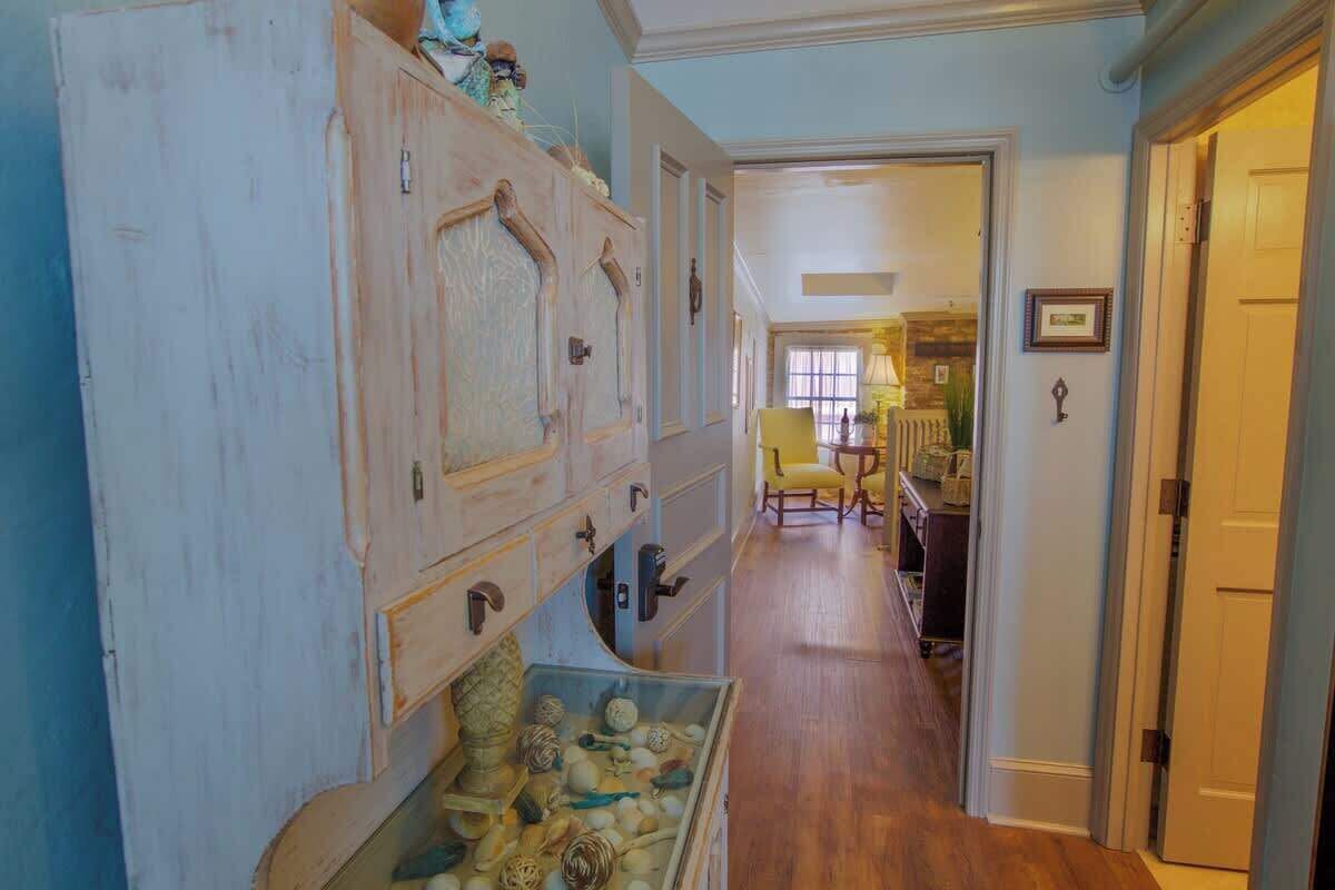 A hallway with a vintage wooden cabinet, a small table with chairs, and a door leading to another room.