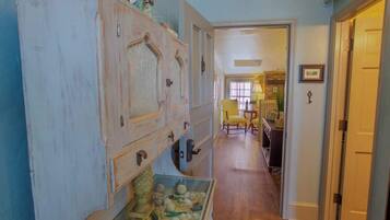 A hallway with a vintage wooden cabinet, a small table with chairs, and a door leading to another room.