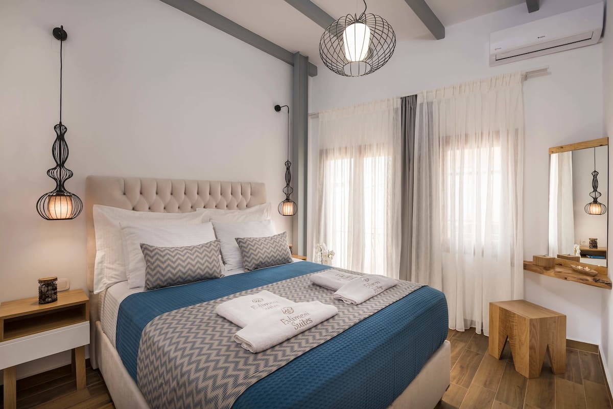 A neatly arranged bedroom with a large bed, bedside tables, a mirror, and a hanging light fixture.