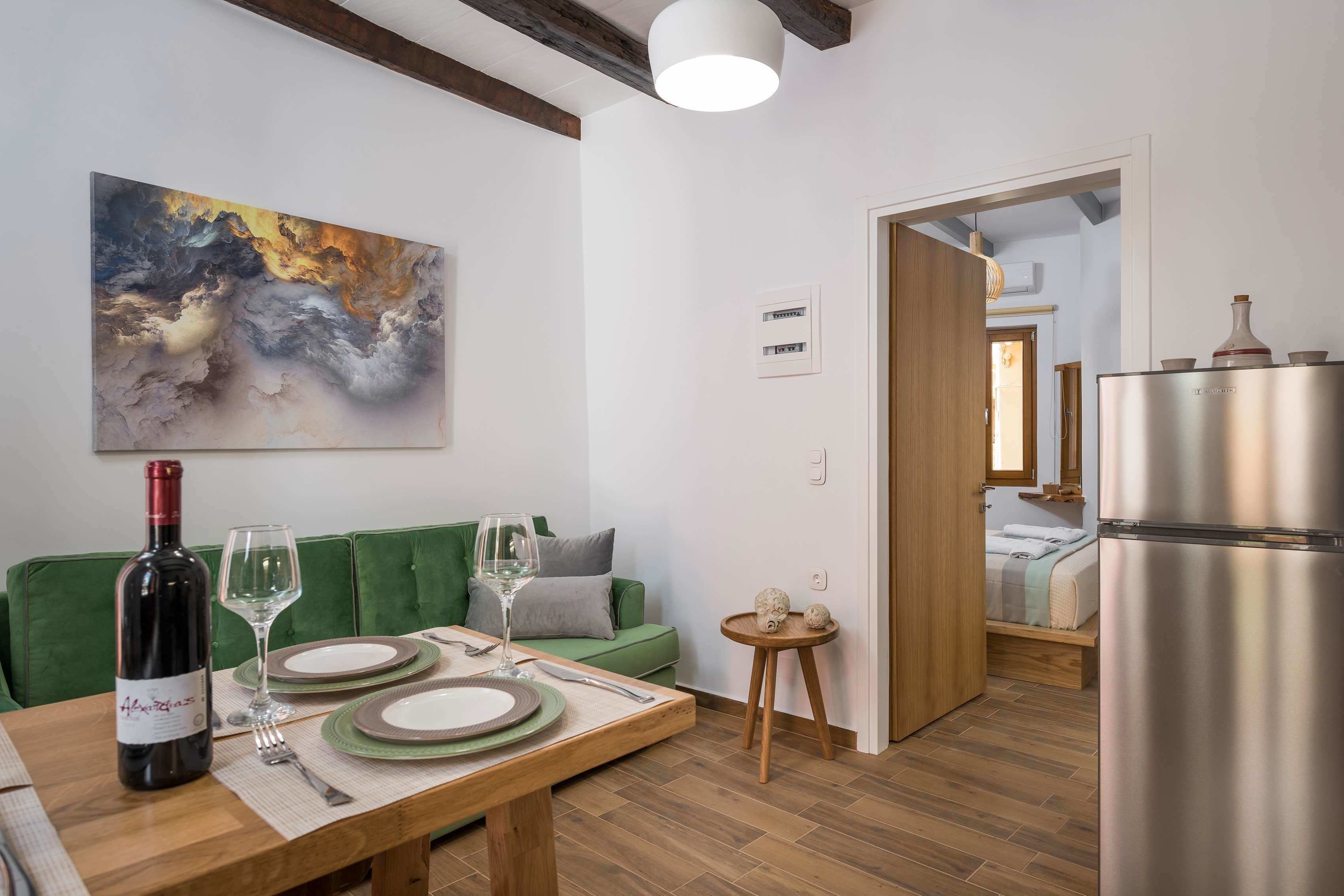 A modern kitchen with a dining area, a green sofa, and a large abstract painting on the wall.