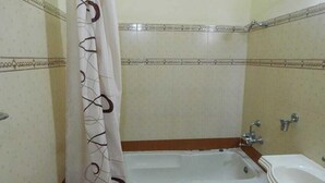 A bathroom with a bathtub, a sink, and a shower curtain. - Hotel Grace (Gwalior)
