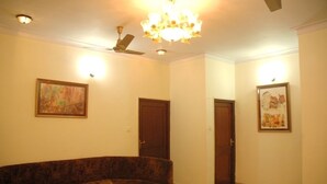 A living room with a brown sofa, two doors, and two framed artworks on the walls. - Hotel Grace (Gwalior)