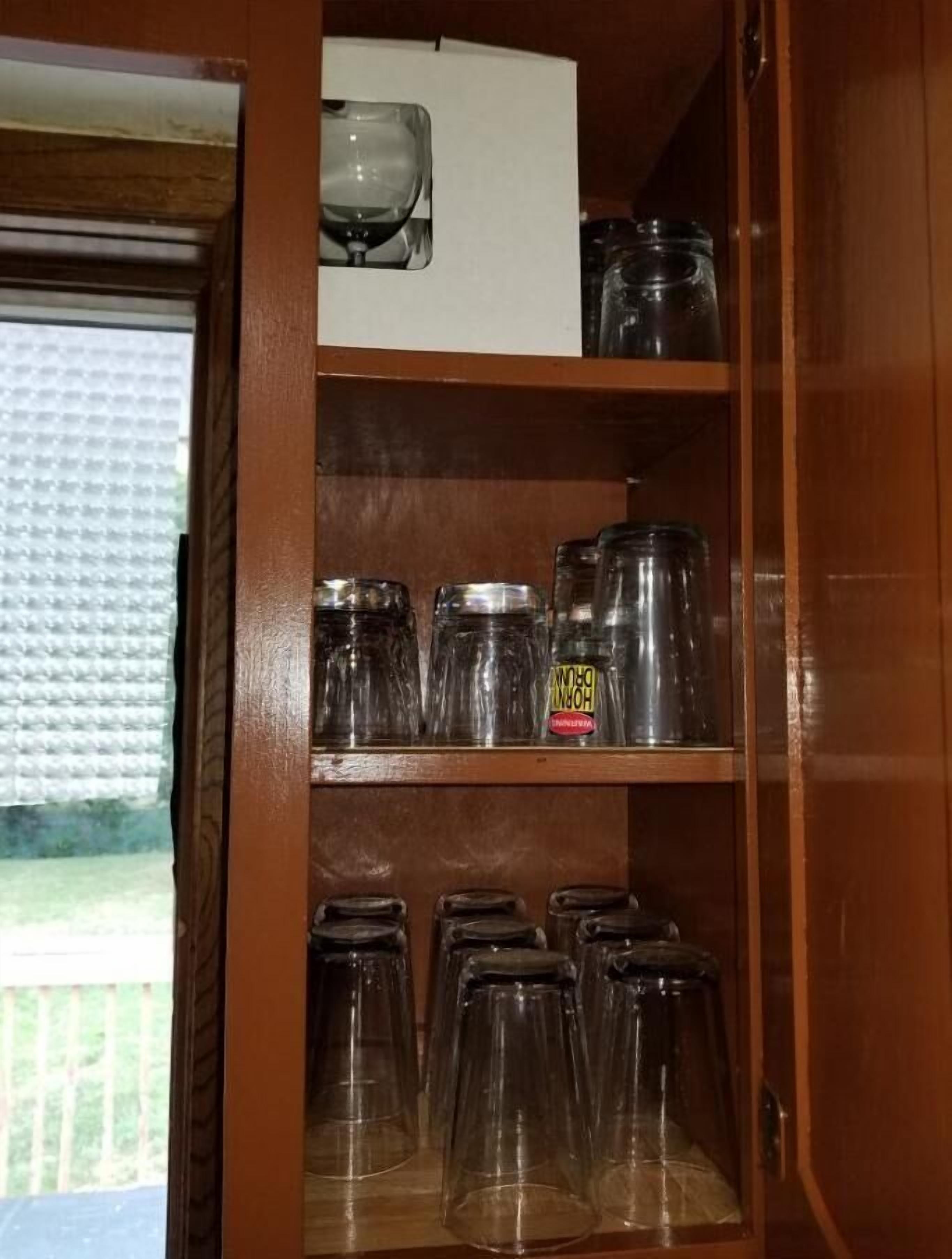 Un armario de madera con estantes que contienen frascos de vidrio y una caja blanca.