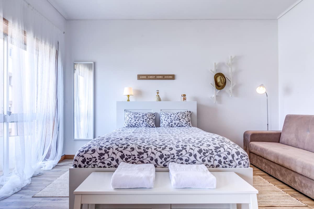 A bedroom with a bed, bedside tables, a sofa, and a sign on the wall.