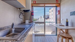 Eine moderne Küche mit einer großen Spüle, einem Holztisch und Blick auf die Stadt durch eine Glastür.