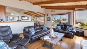 A spacious living room with leather sofas, a wooden coffee table, and a large window offering a view of the sea. - Beautiful South Harbor Home with Great Ocean Views  Point View House (Bodega Bay)