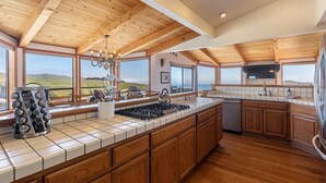 A spacious kitchen with wooden beams, a large island, and a view of the hills. - Beautiful South Harbor Home with Great Ocean Views  Point View House (Bodega Bay)