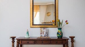 Un aparador de madera con un espejo, una pequeña estatua, un jarrón decorativo y un cuadro con la Torre Eiffel.