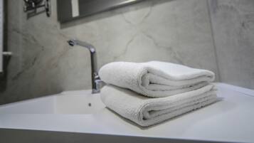 A bathroom with a white sink, a mirror, and a towel stack.