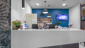 A hotel reception area with a modern design, featuring a reception desk, seating area, and a television screen. - Hotel Park 45 (Zagreb)