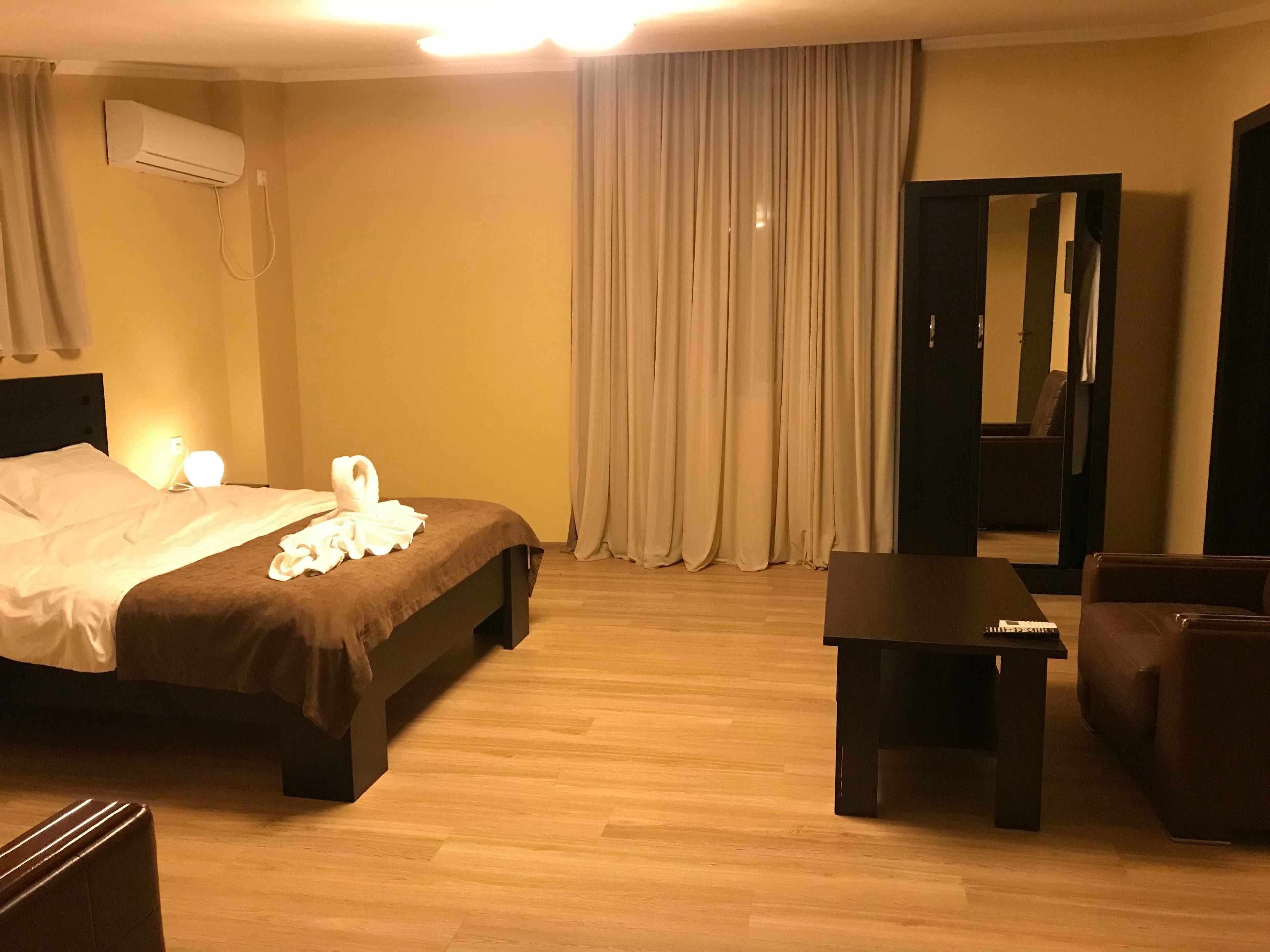 Una habitación de hotel con una cama, una mesita de noche, una silla, un escritorio y un espejo.