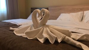 A bed with a towel arranged in a heart shape.