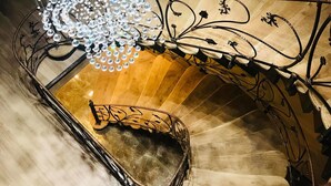 A staircase with a metal railing and a chandelier with hanging crystals.