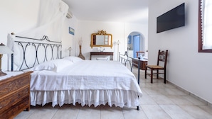 A bedroom with a bed, bedside table, lamp, and a mirror. - Villa Notos (Milos)