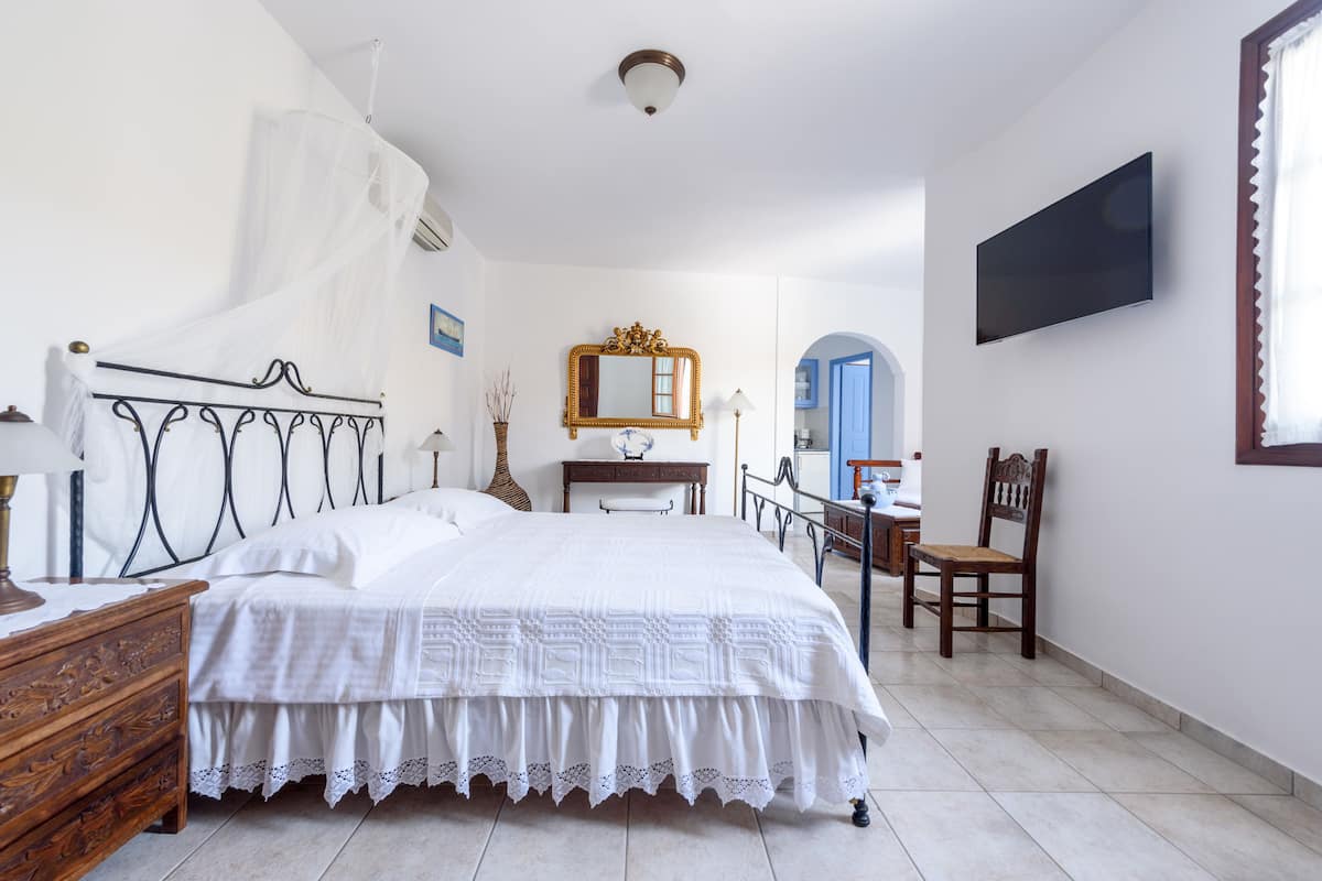 Un dormitorio con cama, mesita de noche, lámpara y espejo.
