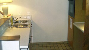 A small kitchen with a stove, sink, and a microwave. - Gästehaus Siebenschläfer (Ludwigsburg)