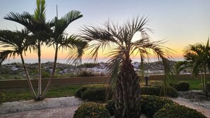 Ein angelegter Garten mit Palmen und Blick auf den Strand bei Sonnenuntergang.