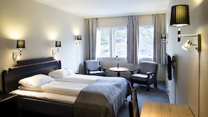 A hotel room with a bed, two armchairs, a small table, and a lamp. - Motell Nor-Kro (Nes)